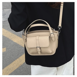 Detail of beige lychee pattern leather bucket bag with front pocket and shoulder strap