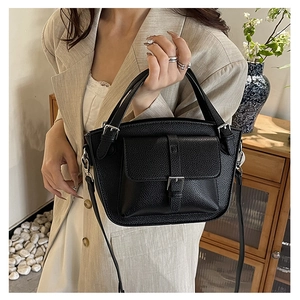 Detail of black lychee grain leather bucket bag with handle and adjustable strap