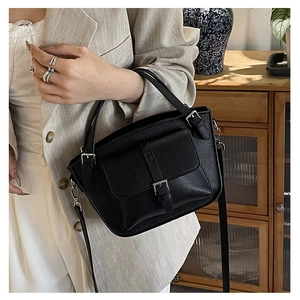 Close-up of black litchi leather bucket bag with silver buckle pocket and top handle