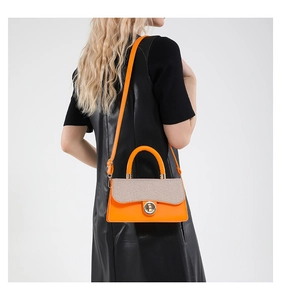 Detail of orange faux leather handbag with beige woven texture and silver metal clasp
