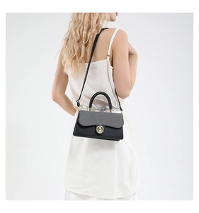 Close-up of contrast color handbag with gray textured flap and golden metal clasp