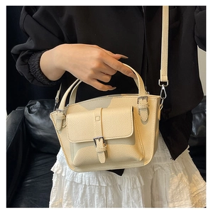 Detail of beige litchi grain leather bucket bag with top handle and adjustable strap