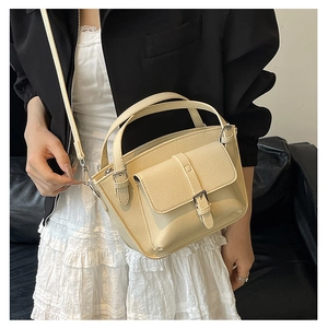 Detail of beige bucket bag in lychee pattern leather with silver hardware and front pocket