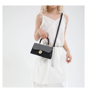 Detail of color-block handbag with gray knit texture flap and gold lock worn by a model