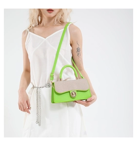 Detail of contrast stitch handbag with gold metal twist lock and neon green leather trim
