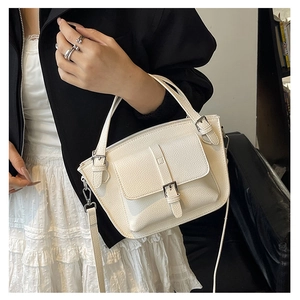 Detail of white lychee pattern leather bucket bag with silver buckle and shoulder strap