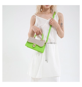 Detail of green crossbody bag with gold textured flap and round metallic twist lock