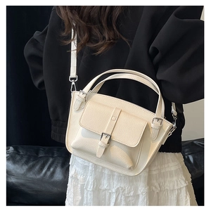 Model wearing a cream bucket bag with lychee texture and silver hardware accents