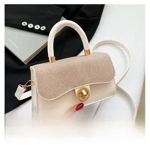 Detail of white mini crossbody bag with brown woven flap and golden twist lock closure