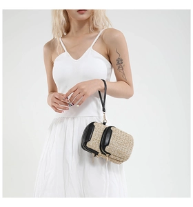 Detail of hand-woven straw mini wristlet with black leather trim and gold zippers