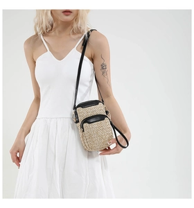 Detail of hand-woven straw phone bag with black leather piping and metal zipper
