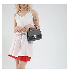 Close-up of black lychee grain leather handbag featuring a golden metallic twist lock