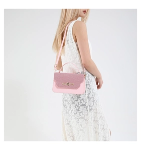 Close-up of pink crossbody bag with woven texture flap and golden rotating lock
