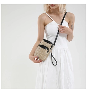 Detail view of mini woven crossbody bag with black leather trim on model in white dress