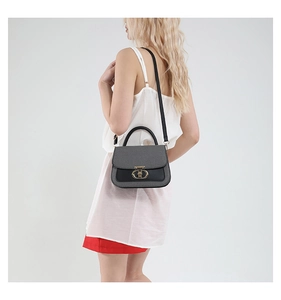 Detailed view of color-block flap bag with woven texture and gold oval lock shown on model