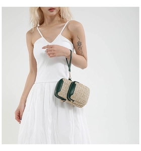 Detail of a woven straw phone bag with green leather trim and double zipper compartments