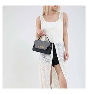 Detail of grey lizard-textured flap and gold metal buckle on a black patchwork handbag
