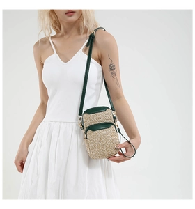 Detail of summer straw crossbody phone bag with dual zip layers and green leather trim