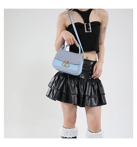 Detailed close-up of light blue and grey woven leather bag with gold T-bar metal clasp