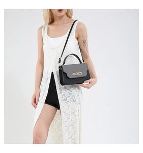 Detail of trendy color-block handbag showing golden metal twist lock and gray PU flap