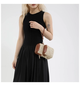 Detail of woven straw mini bag with double zippers and brown leather trim on wristlet
