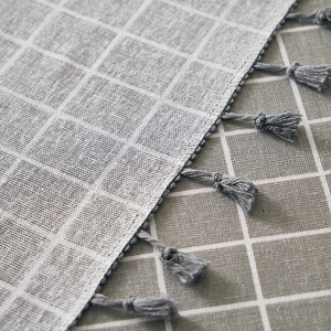 Close-up of gray and white checkered cotton linen tablecloth with decorative tassel fringe