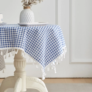 Blue and white gingham cotton linen tablecloth with elegant white fringe tassels on a table