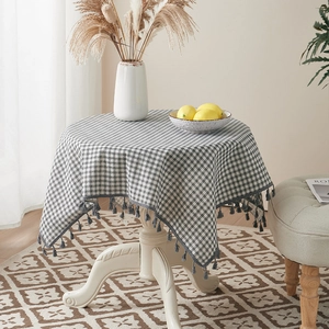 Detail of grey gingham tablecloth with fringe tassels on white round table