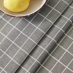 Close-up of grey linen tablecloth with white grid pattern and fresh lemon table decor