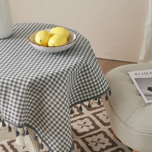 Classic grey checkered cotton linen tablecloth with fringe tassels on a round dining table