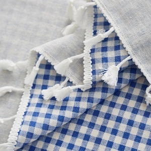 Detail of blue gingham cotton linen tablecloth with white lace edges and fringe tassels