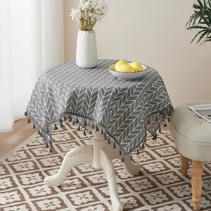 Detail of grey arrow pattern tablecloth with decorative tassels on a round table