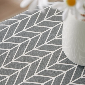 Detail shot of grey arrow pattern cotton linen tablecloth with a white ceramic vase