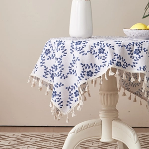 Floral cotton linen tablecloth with blue flowers and tassels on a round white table