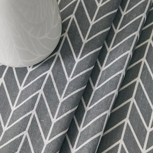 Detail of gray cotton linen tablecloth featuring a geometric arrow herringbone pattern texture