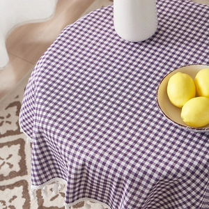Detail of purple gingham cotton linen tablecloth featuring decorative white tassel edges