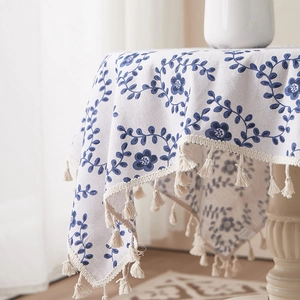 Detail of floral linen tablecloth with blue pattern prints and ivory tassel edges
