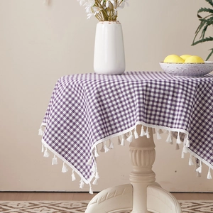 Detail of purple plaid linen tablecloth featuring delicate white handmade tassel edges
