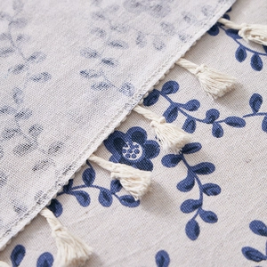Detail of floral linen tablecloth featuring vintage blue patterns and handmade tassels