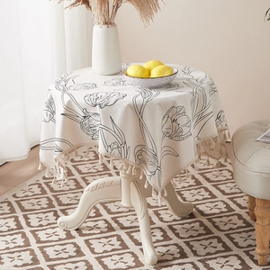 Detail of tulip printed cotton linen tablecloth with elegant fringe tassels on round table