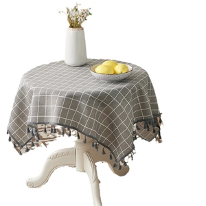 Linen cotton tablecloth with grey check pattern and tassels on a round dining table