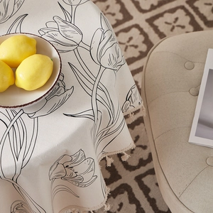 Detail of white linen tablecloth featuring black tulip sketches and handcrafted tassels