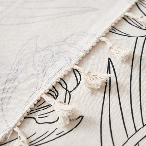 Linen tulip tablecloth with black floral patterns and decorative fringe edges