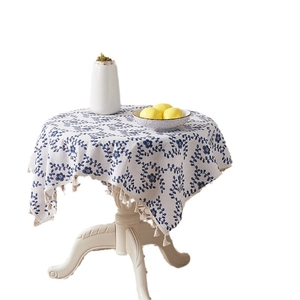 Floral cotton linen round tablecloth with blue vines, beige tassels, and white backdrop