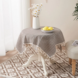 Close-up of brown checkered cotton linen tablecloth with elegant fringe tassel details
