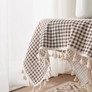 Brown and beige plaid cotton linen tablecloth with elegant tassels in a cozy home setting