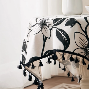 Detail of floral linen tablecloth featuring black hand-drawn prints and decorative fringes