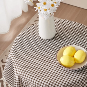 Brown and white plaid cotton linen tablecloth with tassel edges on a round dining table