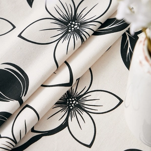 Detailed texture of cotton linen tablecloth with black floral patterns on beige fabric