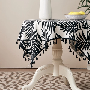 Detailed view of tropical palm leaf print tablecloth with black decorative tassels